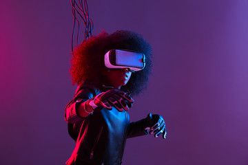 Mod curly dark haired girl dressed in black leather jacket and gloves uses the virtual reality...