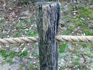 Obraz premium Wooden fence column with a rope that goes through the whole in it.