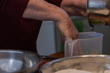 pressing shredded zucchini into a clear plastic measuring cup