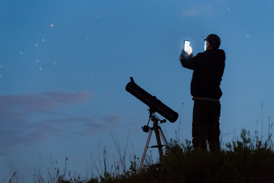 Young man sets up a telescope using a smartphone