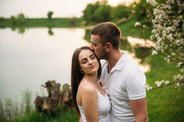 Dating in park. Love couple standing together on grass near the lake. Romance and love