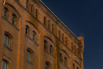 Facade of the old mill building at nighttime. Building of red brick