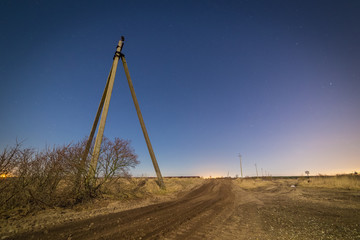 Fototapeta premium Dirt road and old power line towers at night