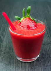 VASO DE CRISTAL CON ZUMO DE FRESA SOBRE FONDO DE MADERA GRIS