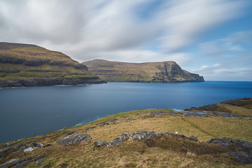 Epic landscape picture in Faroe islands shown open scandinavian countryside without trees, but with moorland, meadows and huge cliffs in wild north atlantic ocean.