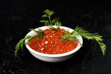 Red caviar in  bowl, dark background