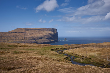 Epic landscape picture in Faroe islands shown open scandinavian countryside without trees, but with moorland, meadows and huge cliffs in wild north atlantic ocean.
