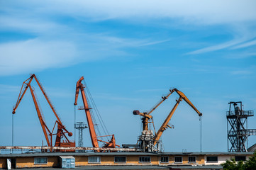 Industrial scene with crane and river port facilities on blue sky background