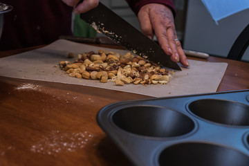 mixed nuts on a table being chopped near a muffin tray