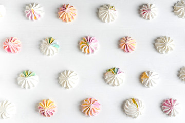 Multi-colored meringue on a white background. Sweets on the photo. Pattern with meringue on a white background. Sweet holidays