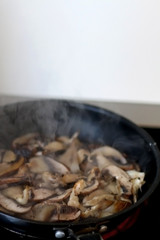 Frying oyster mushrooms and champignong in a pan with olive oil. Selective focus. 