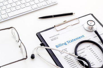 phonendoscope, billing statement and keyboard on work desk of doctor in hospital white background