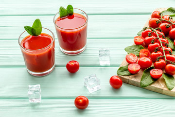 summer cocktails for freshness with red tomato and ice on mint green wooden background