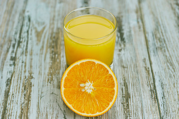 a glass of fresh orange juice with fresh citrus fruits on a light wooden table. horizontal view. citrus juice