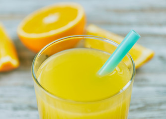 a glass of fresh orange juice with fresh citrus fruits on a light wooden table. horizontal view. citrus juice