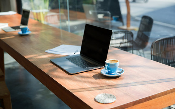 Two laptops on a table at a cafe