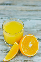 A glass of fresh orange juice with orange slices on a light wooden table close-up. copying text.