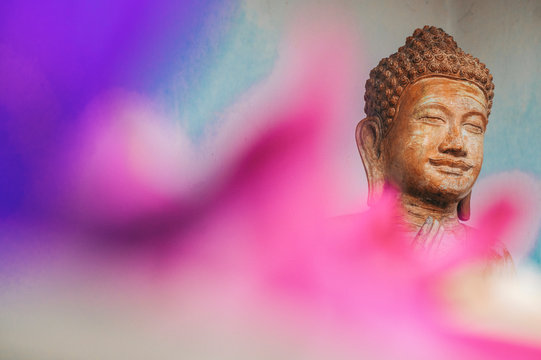 Stone carved statue of Buddha surrounded with colorful flowers