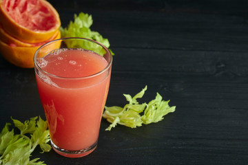 fresh citrus grapefruit juice in a glass. On a black wooden table. Black background. horizontal view. place for text.