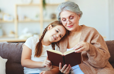 happy family grandmother reading to granddaughter book at home - Powered by Adobe