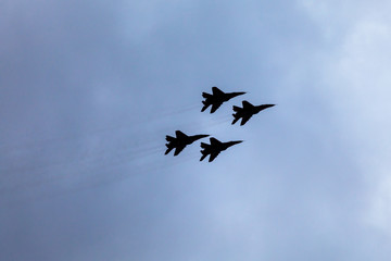 The contours of four combat aircraft against the backdrop of a stormy sky