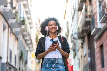 Beautiful Afro American Girl Listening Music on Headphones Outdoors.
