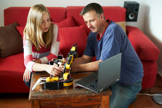 Father teaching daughter how to program a robotic arm