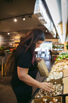 Woman choosing mushrooms in grocery store