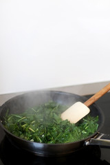 Roasting chicory in a pan with olive oil. Selective focus.