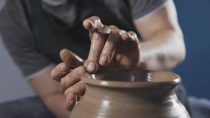 Close up of Hands gently create correctly shaped handmade from clay. Potter creates product on potter's wheel