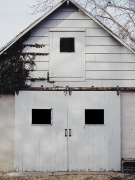 an old barn garage with three window and ivy growing on it