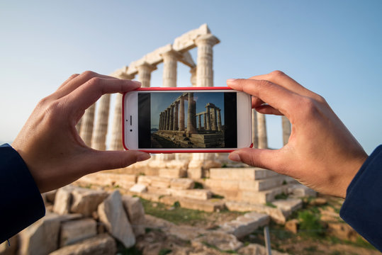 Woman taking photos on the Temple of Poseidon on cape Sounion