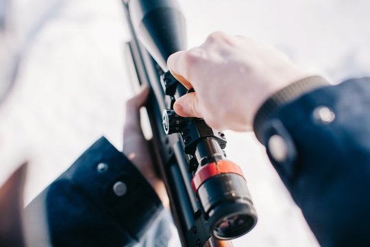 Closeup man's hands fixing the rifle scope