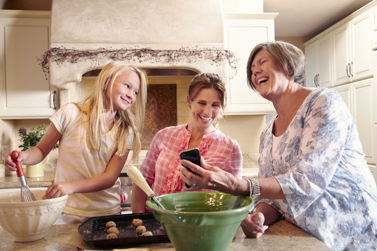Three generations of women cooking together in the kitchen
