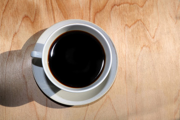 A cup of coffee on a wooden background, the coziness of a new country house and a sunny bright morning