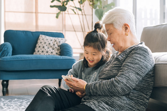 Senior grandmother using smartphone with her granddaughter