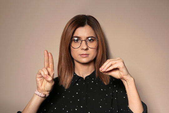 Woman using sign language on color background