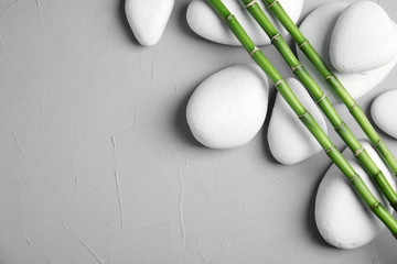 Zen stones and bamboo on grey background, top view with space for text