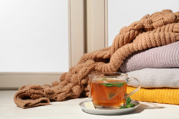 Cup of fresh tea on windowsill indoors, space for text. Winter drink