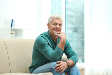 Fototapeta premium Portrait of handsome mature man on sofa indoors