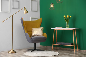 Modern interior with comfortable armchair and table near color wall