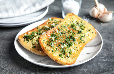 Plate with delicious homemade garlic bread on table
