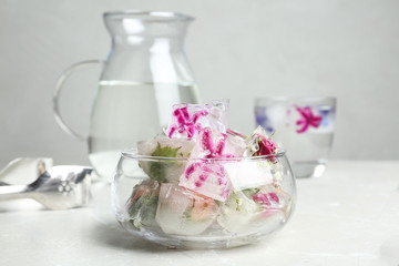 Glass bowl of floral ice cubes on table