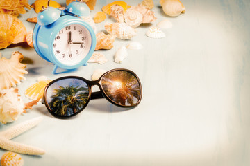background with alarm clocks, sunglasses and seashells, summer holiday and vacation time concept