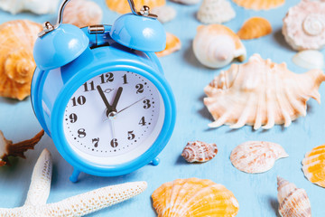 Blue sea background with alarm clocks and seashells, summer holiday and vacation time concept