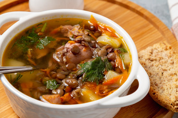 Lentil soup with chicken in a white bowl on a wooden board