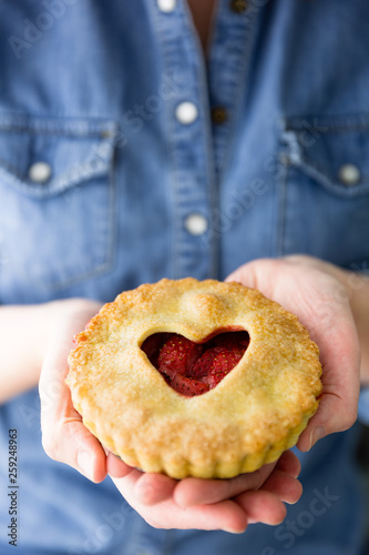 Woman holding a strawberry pit with heart on top of crust