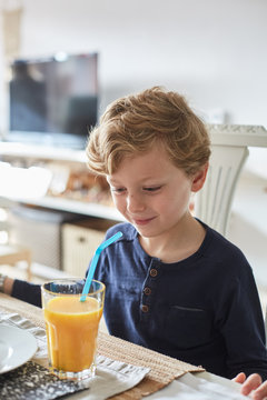 Happy child enjoying orange juice and breakfast at home