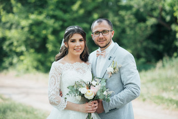 Wedding photo of the bride and groom in a gray-pink color on nature in the forest and rocks.