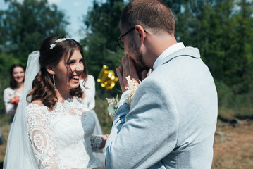 Wedding photo of the bride and groom in a gray-pink color on nature in the forest and rocks.